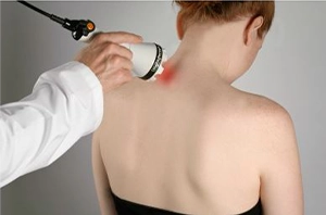 Laser therapy treatment being applied to the upper back and neck area to help reduce pain and inflammation.